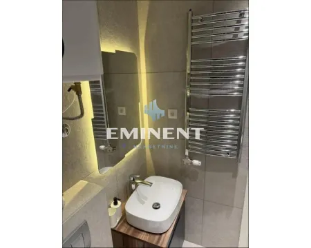 Modern bathroom with a basin, backlit mirror, and a towel rail. - image 6
