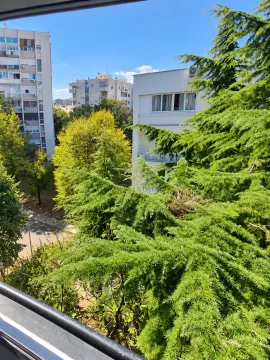 Pogled sa prozora na okolne zgrade i zeleno drveće. - image 7