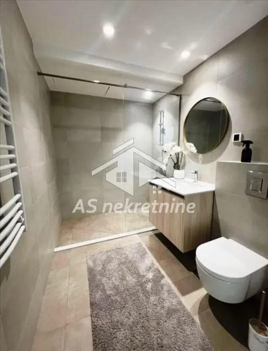 Modern bathroom with a walk-in shower, washbasin, and toilet.
