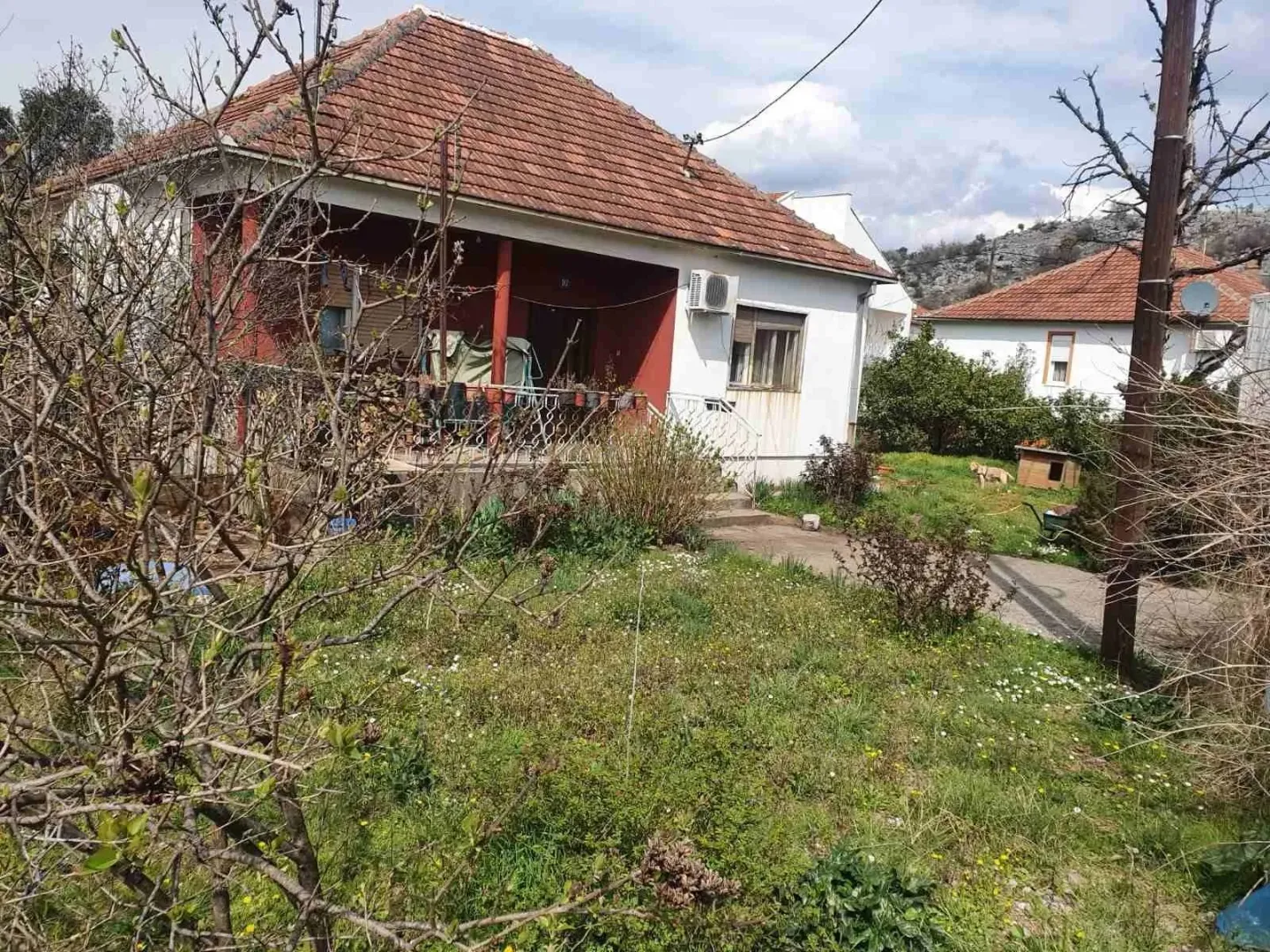 Jednospratna kuća sa dvorištem i crvenim krovom.