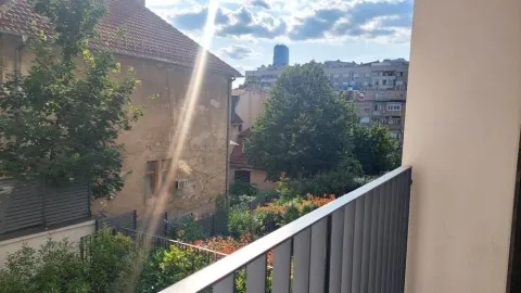 View from the balcony overlooking surrounding buildings and greenery. - image 8