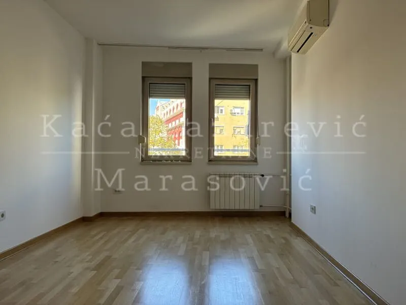 Empty room with parquet flooring and an air conditioning unit on the wall.