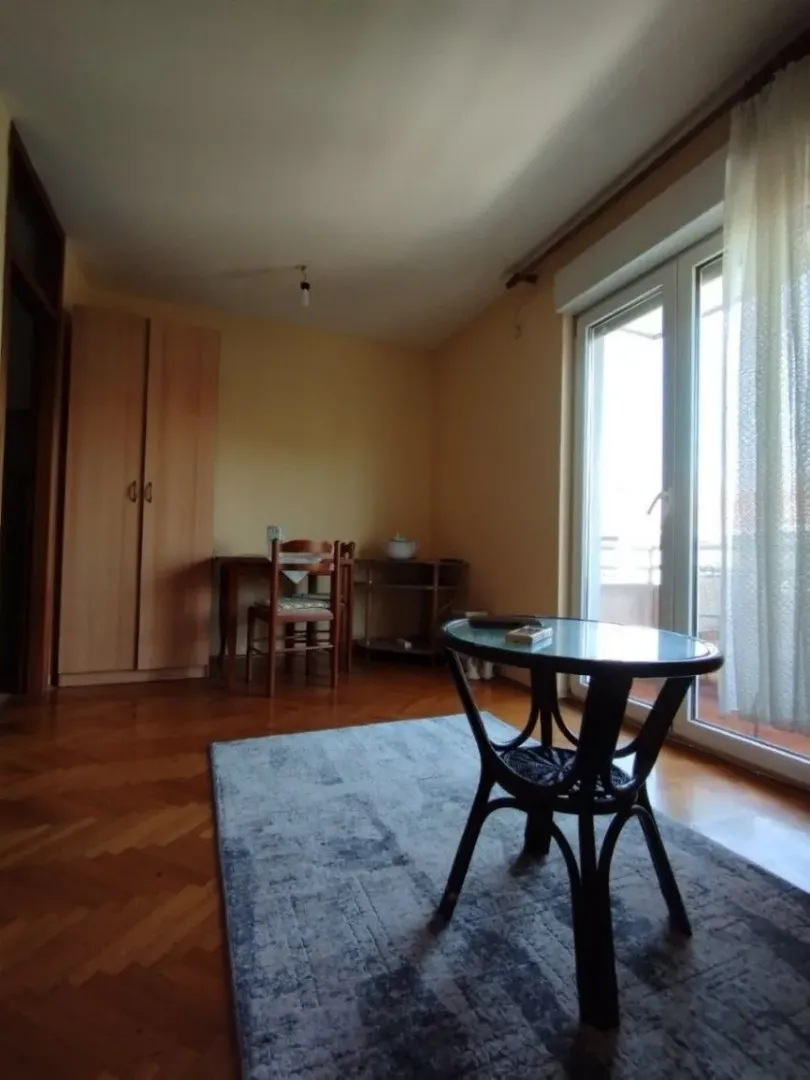 Bright room with wooden furniture, parquet flooring, and balcony access.