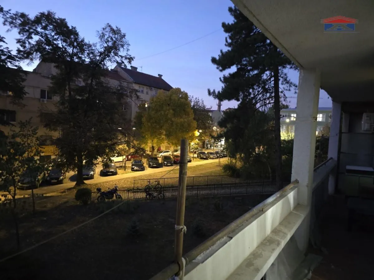 Pogled sa natkrivenog balkona na ulicu i parkiralište u večernjim satima.