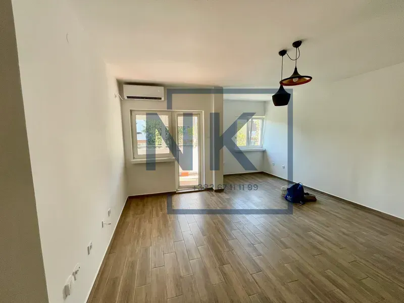 Empty living room with wooden flooring, air conditioning unit, and access to the terrace.