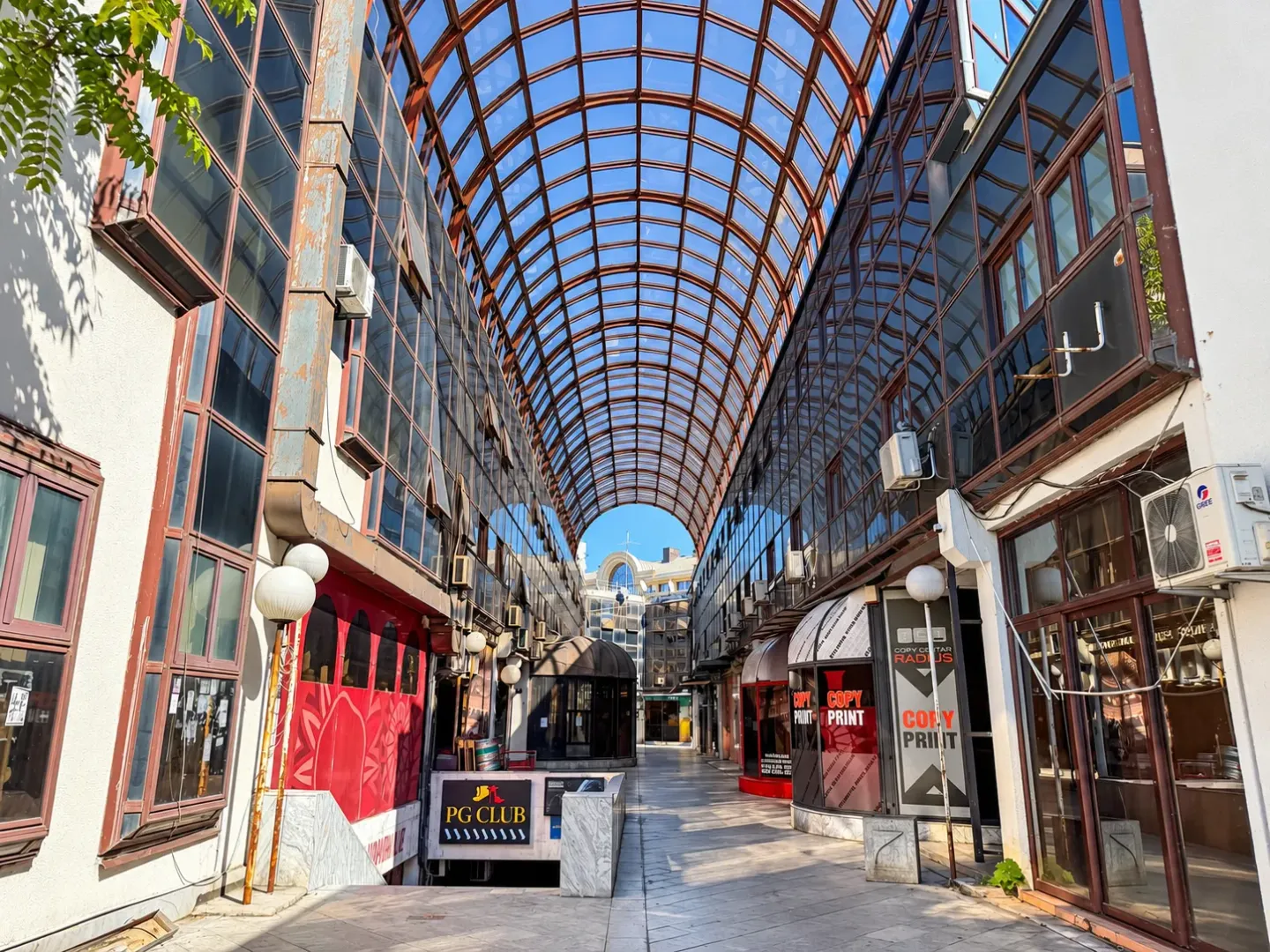 Covered passageway between commercial buildings with a glass roof.