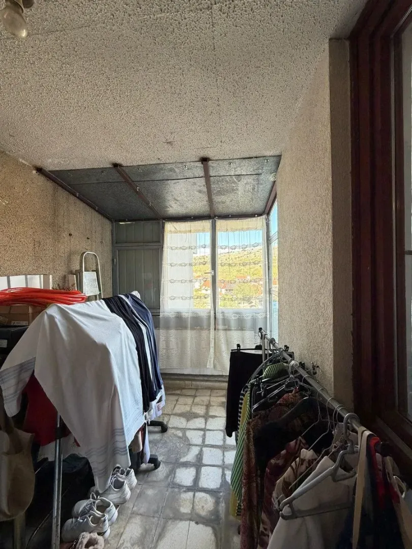 Zastakljena terasa sa sušilicama za veš i neredom.