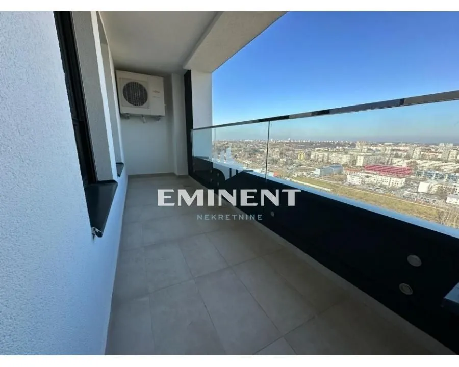Spacious balcony with a glass railing and a city view.
