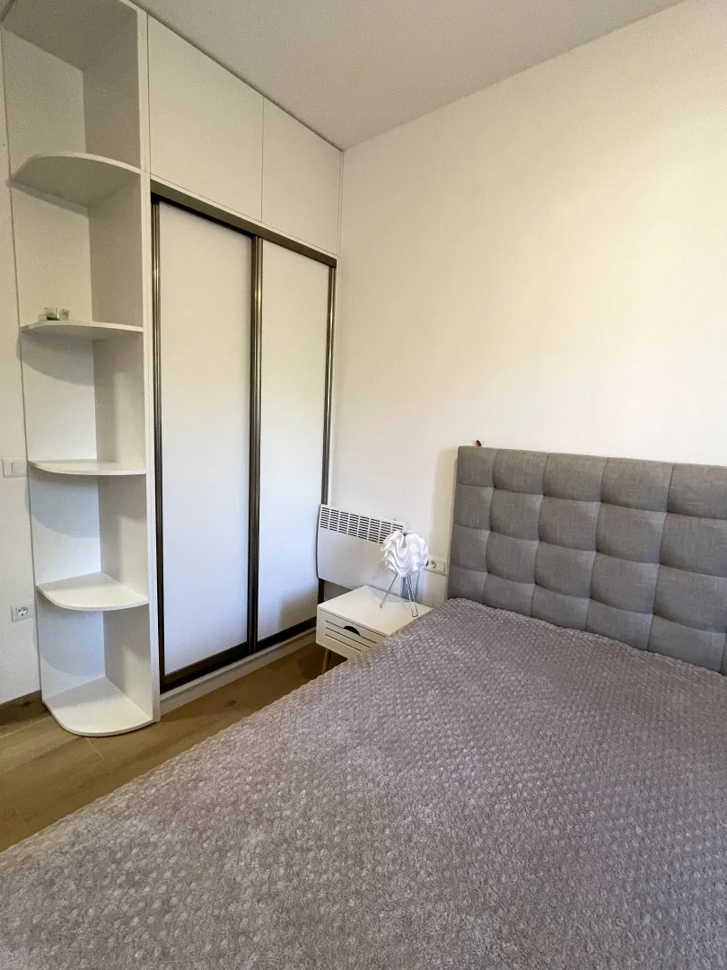 Namještena spavaća soba sa bračnim krevetom i ugradnim plakarom.
