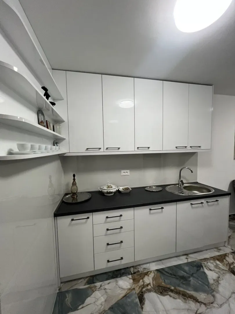 Bright kitchen with white cabinets and a dark countertop.