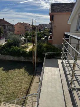 Spacious tiled terrace with a metal railing and a view of the courtyard and surrounding houses. - image 4