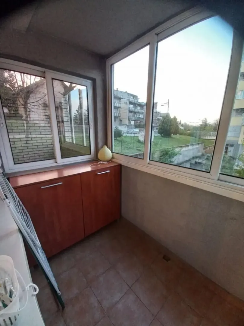 Zastakljena terasa sa drvenim elementom i pogledom na okolinu.