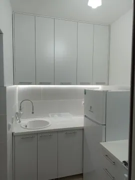 Bijela kuhinja sa sudoperom, radnom pločom i frižiderom. - image 8
