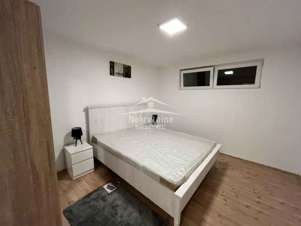 Furnished bedroom with a white bed and a nightstand.