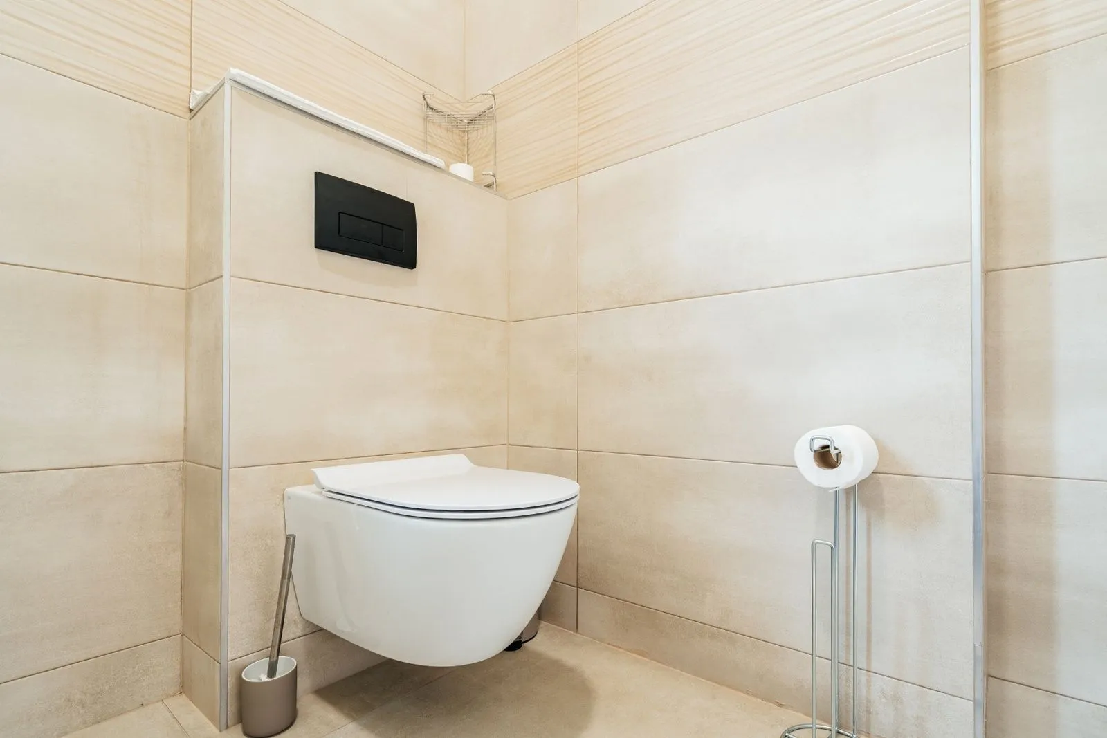 Modern wall-hung toilet with beige tiles.