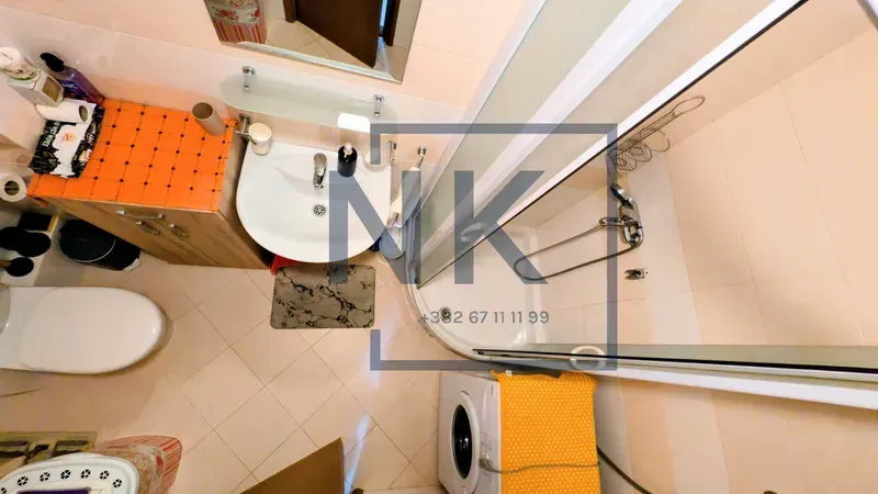 Top-down view of a furnished bathroom with a shower cabin and a washing machine.