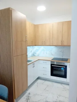 Kuhinja sa drvenim elementima, belim donjim ormarićima i ugradnom rernom. - image 8