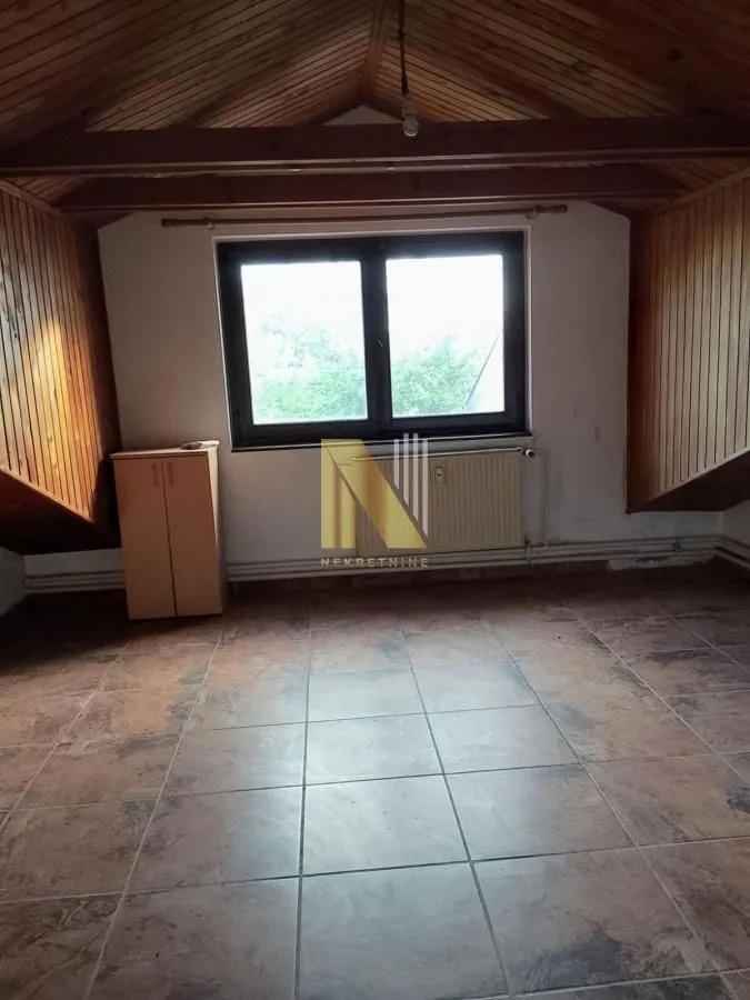 Prazna potkrovna prostorija sa drvenom krovnom konstrukcijom i pločicama na podu.