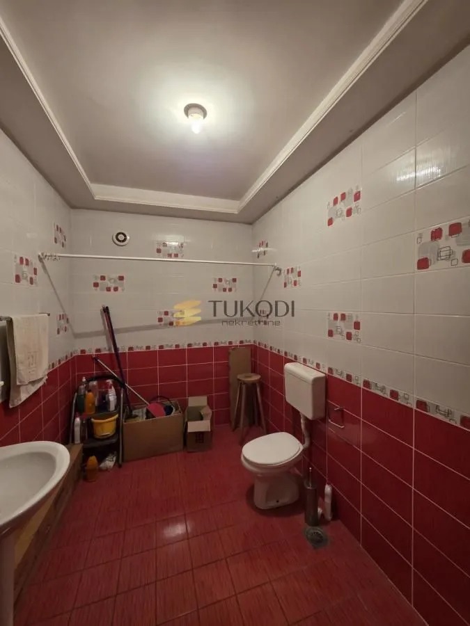 Kupatilo sa keramičkim pločicama u crvenim i belim tonovima i sanitarijama.