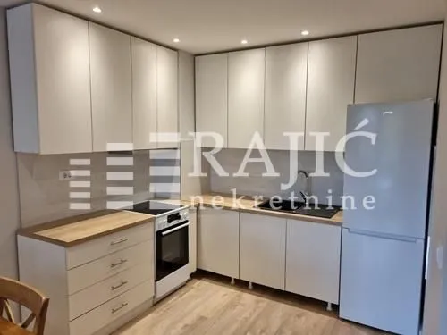 Modern white kitchen with a wooden countertop and built-in appliances.