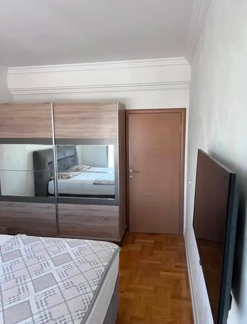 Spavaća soba sa velikim plakarom, krevetom i televizorom na zidu.