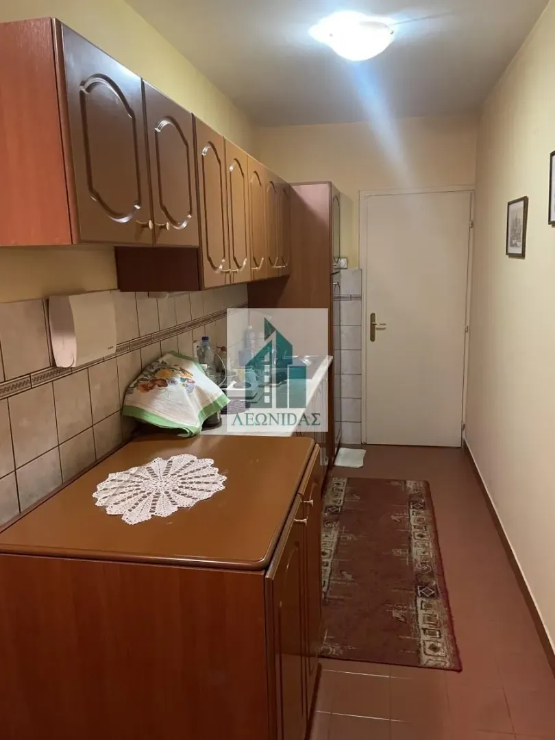 Small kitchen with brown wooden cabinets and wall tiles.