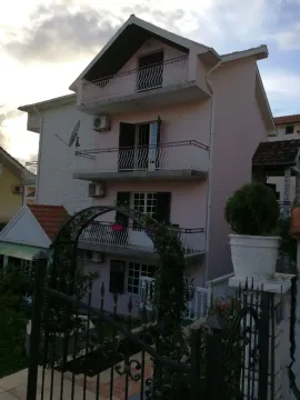 Trospratna kuća sa balkonima i kapijom u prednjem planu. - image 14