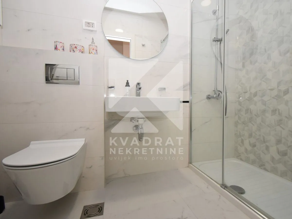 Modern bathroom with a shower cabin, washbasin, and built-in toilet.
