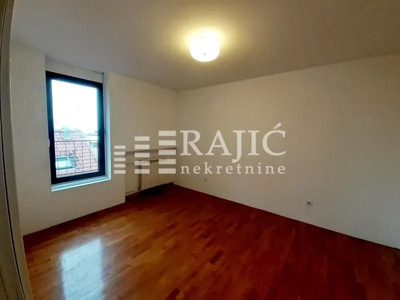 Empty room with parquet flooring and a window.