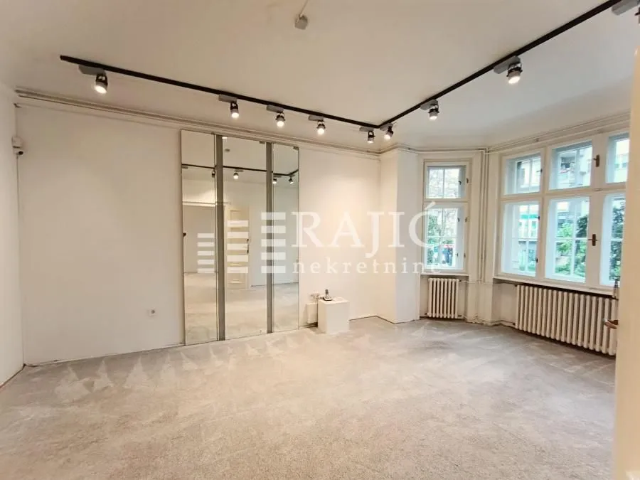 Empty bright room with carpeting, mirrors, and ceiling track lighting.