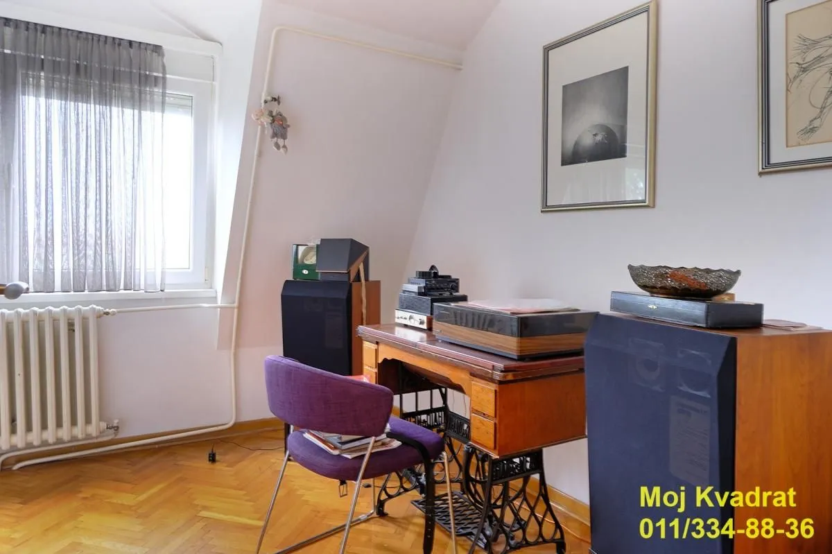 Manja soba sa radnim stolom, stolicom i zvučnicima ispod prozora.