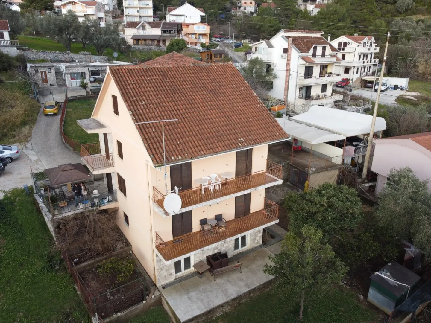 An aerial view of a three-story house with balconies and a yard.