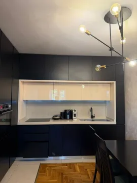 Moderna kuhinja sa crnim elementima i trpezarijskim stolom. - image 3