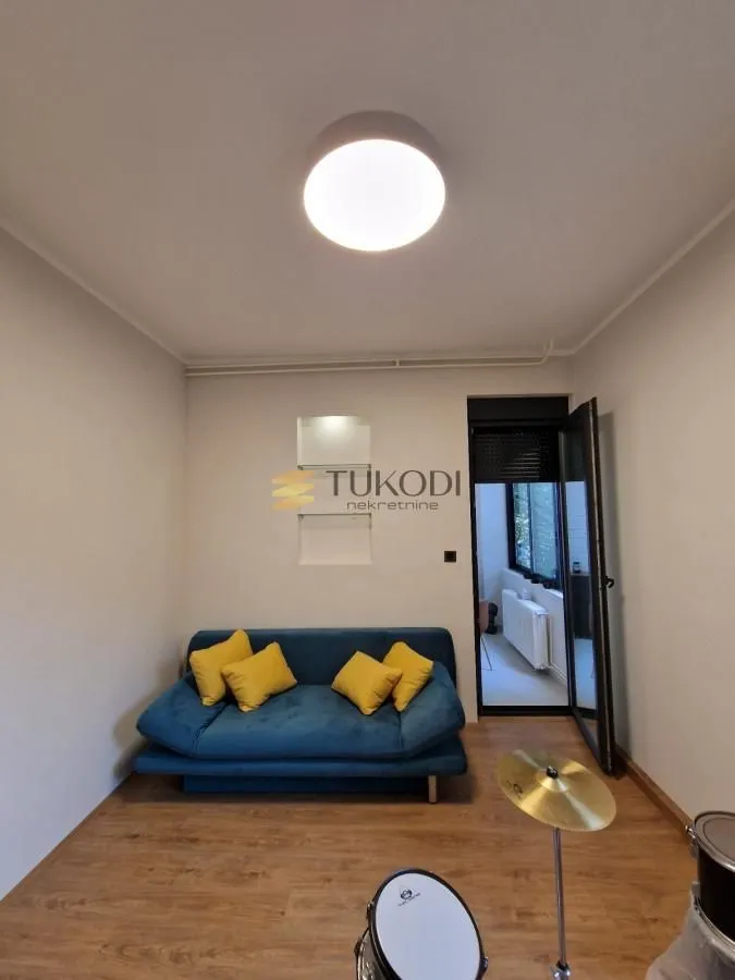 Smaller living room with a blue sofa and access to the terrace.