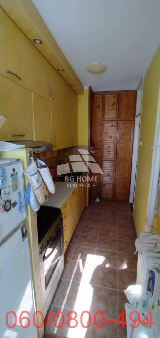 Manja kuhinja sa žutim elementima i ugradnim šporetom.