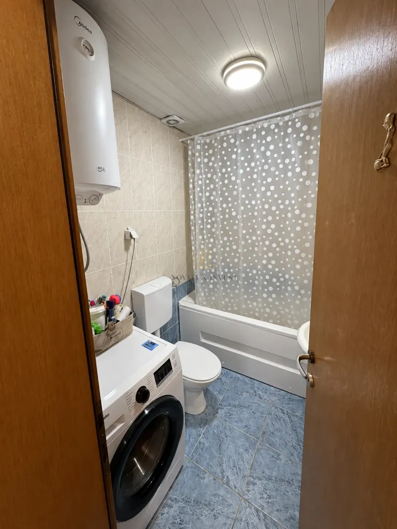 Smaller bathroom with a bathtub, washing machine, and water heater.