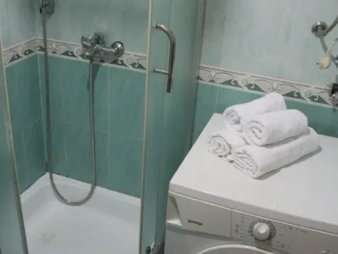 Small bathroom with a shower cabin and washing machine. - image 9