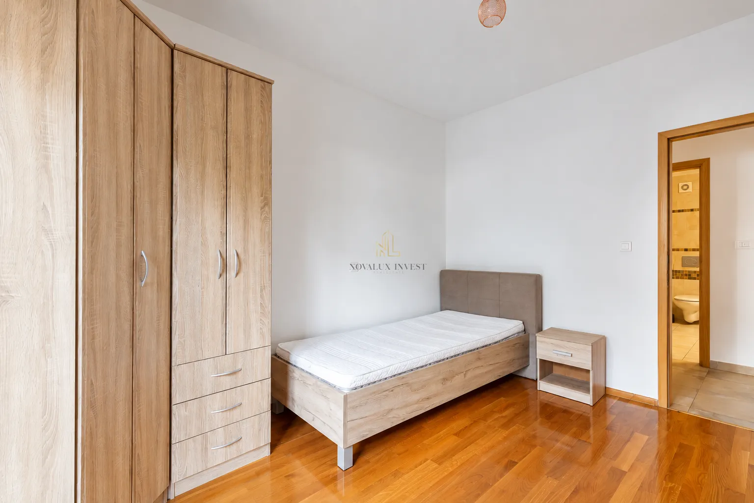 Bedroom with a single bed, wooden wardrobe, and a nightstand.
