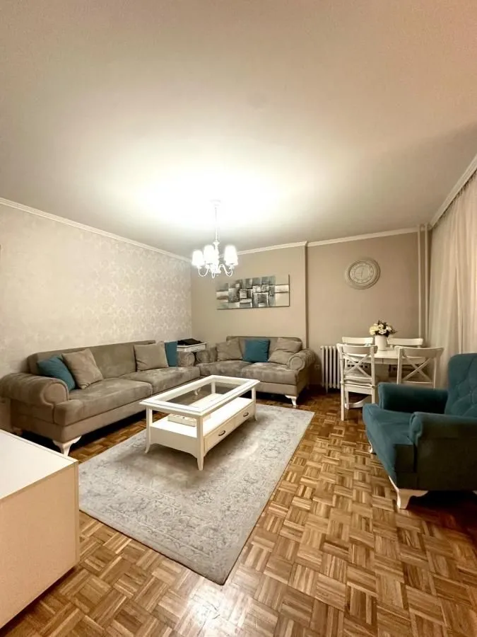 Dnevna soba sa garniturom, stočićem i trpezarijskim stolom u uglu.