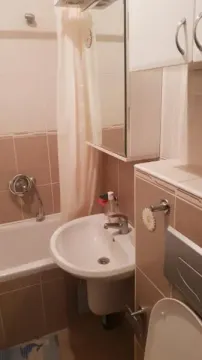 Kupatilo opremljeno umivaonikom, kadom sa zavesom, WC šoljom i visećim elementom. - image 19