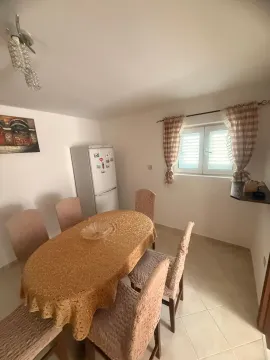 Trpezarija sa stolom, stolicama i frižiderom u uglu. - image 9