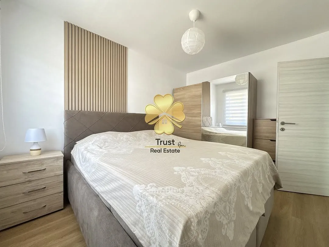 Furnished bedroom with a double bed, wardrobe, and decorative wall panel.