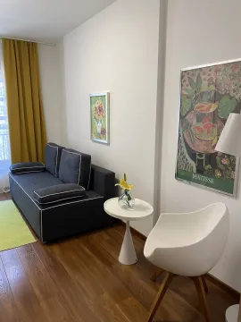 Svijetla dnevna soba sa tamnom sofom, bijelom foteljom i ukrasnim detaljima. - image 6