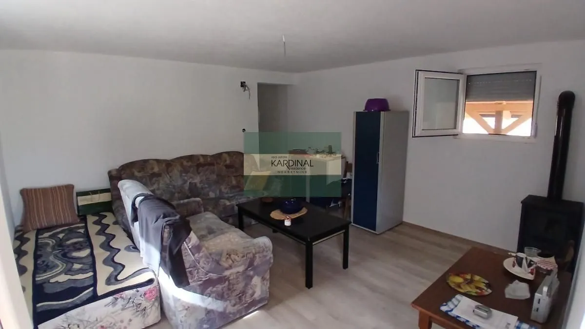 Dnevna soba sa garniturom za sedenje, stočićem i peći na drva.