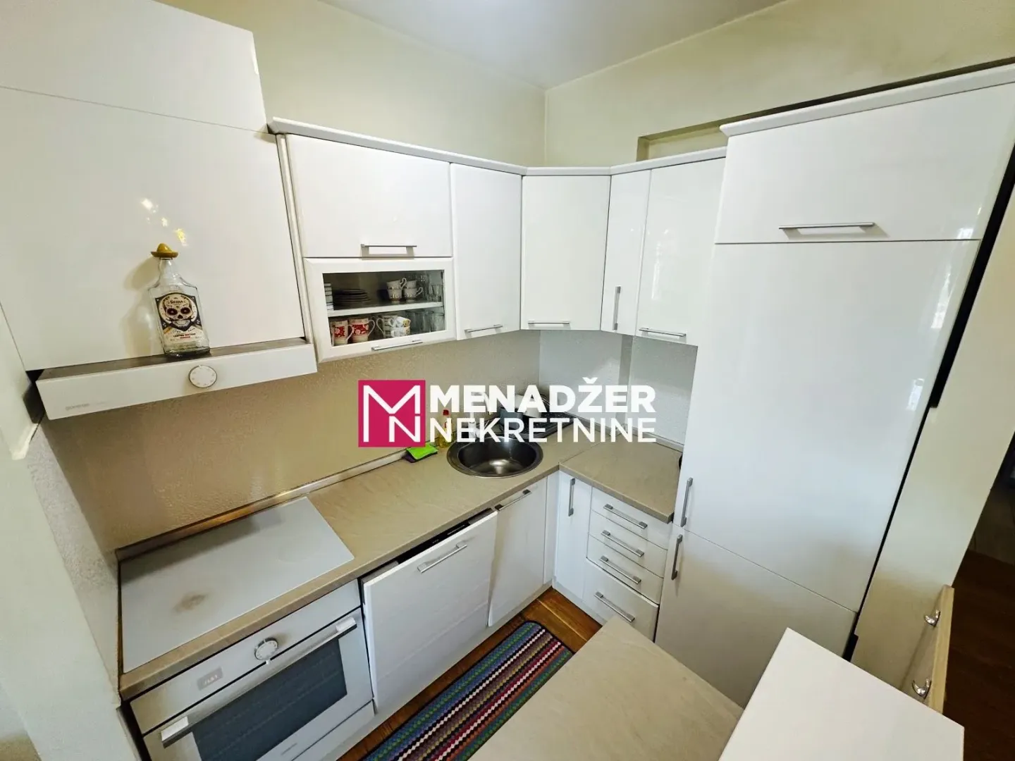 Modern white kitchen with built-in appliances and a sink.