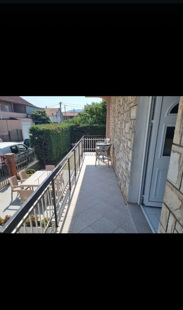 A long tiled terrace with a metal railing and a view of the yard.
