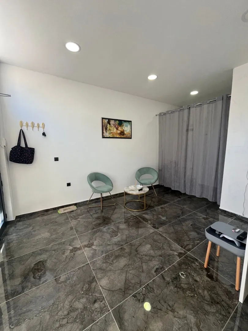 Living room with seating furniture and dark ceramic floor tiles.