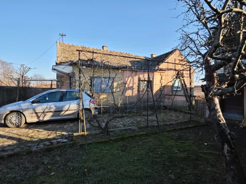 Starija prizemna kuća sa dvorištem i parkiranim automobilom ispred. - image 3