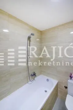 Small bathroom with a bathtub and beige wall tiles. - image 11