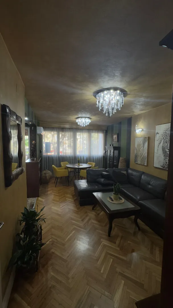 Dnevna soba sa garniturom, trpezarijskim stolom i parketom na podu.